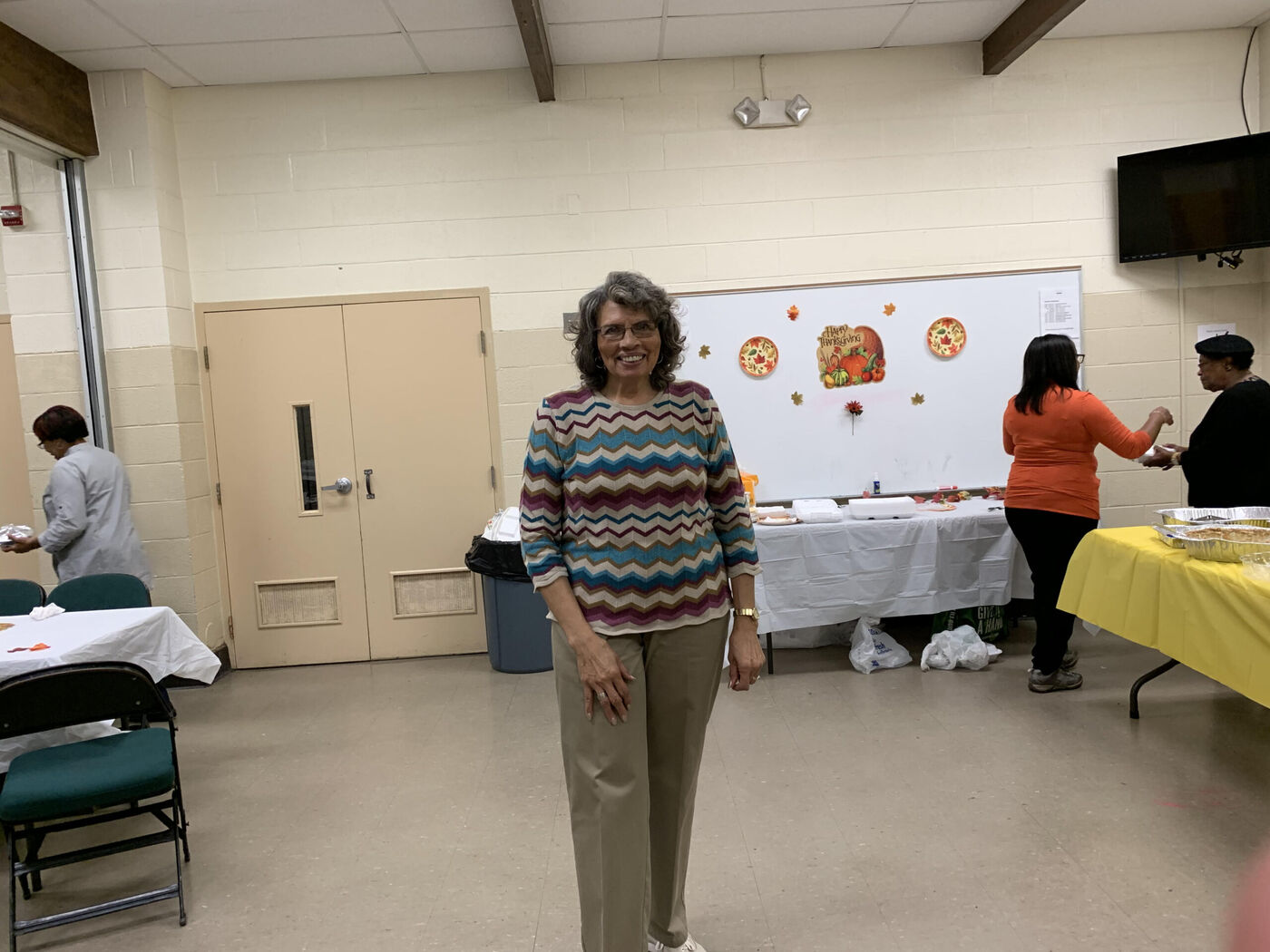 Betty Watson standing in a community room with tables of food behind her