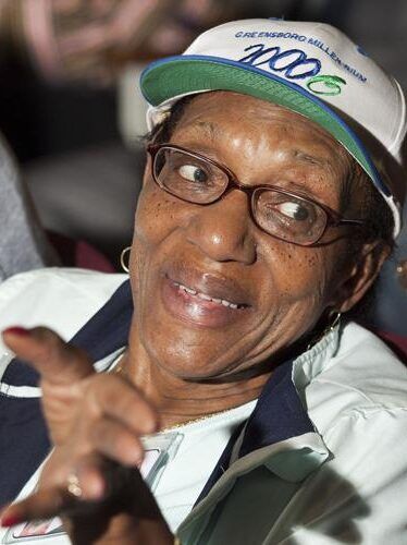Nettie Coad smiling and gesturing, wearing a cap